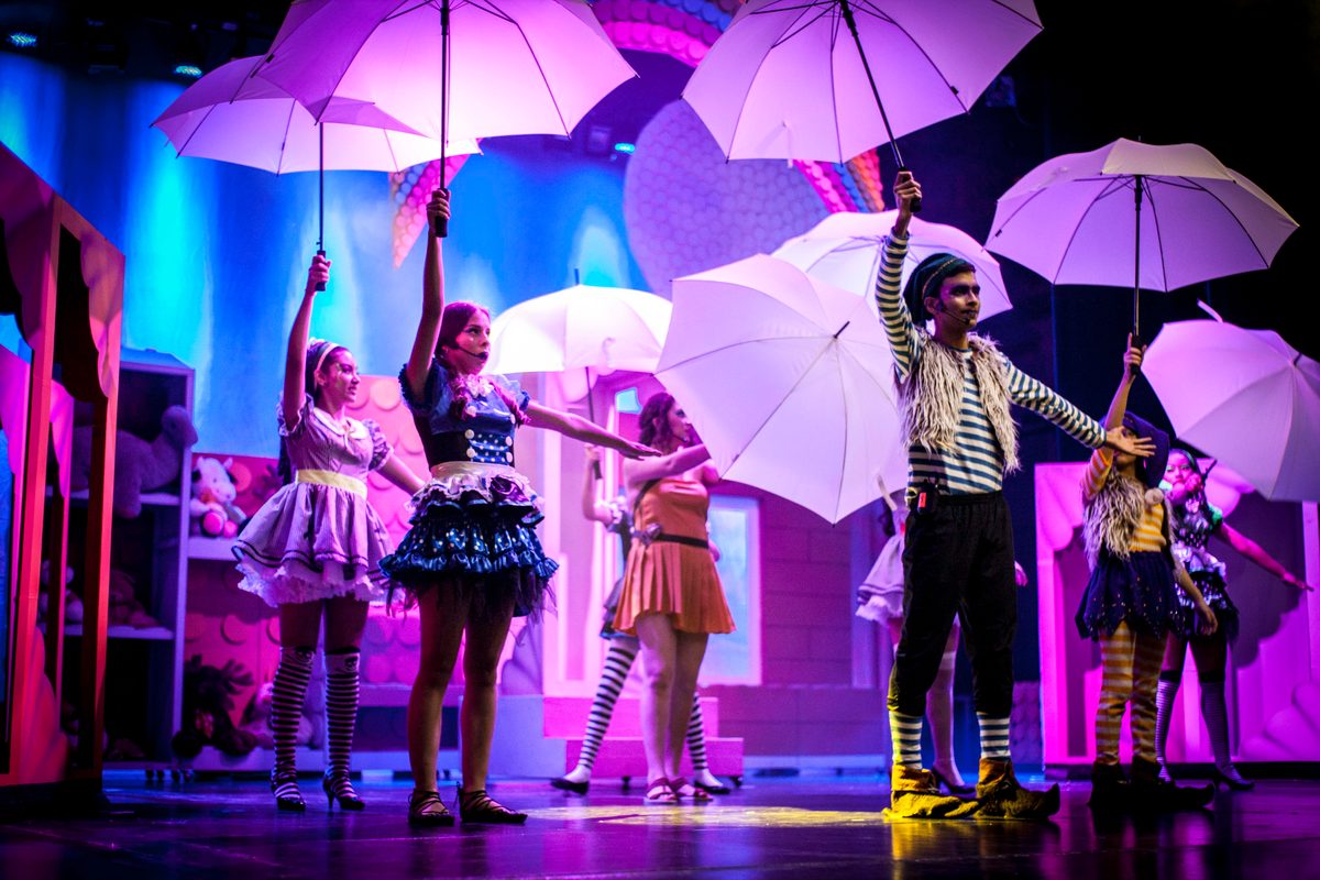 Performers with white umbrellas in a scene with coloured lights