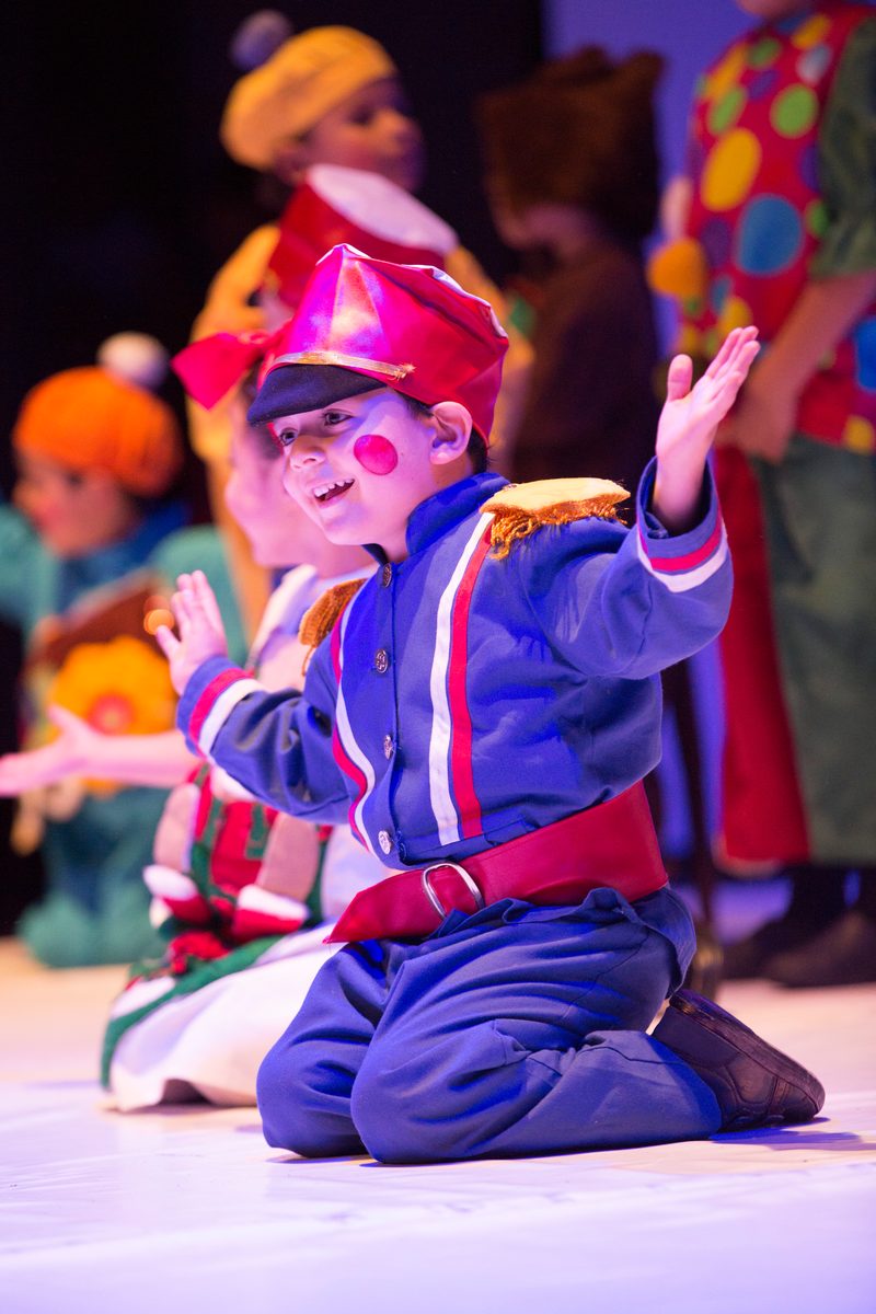 A child in a toy costume, kneeling on stage