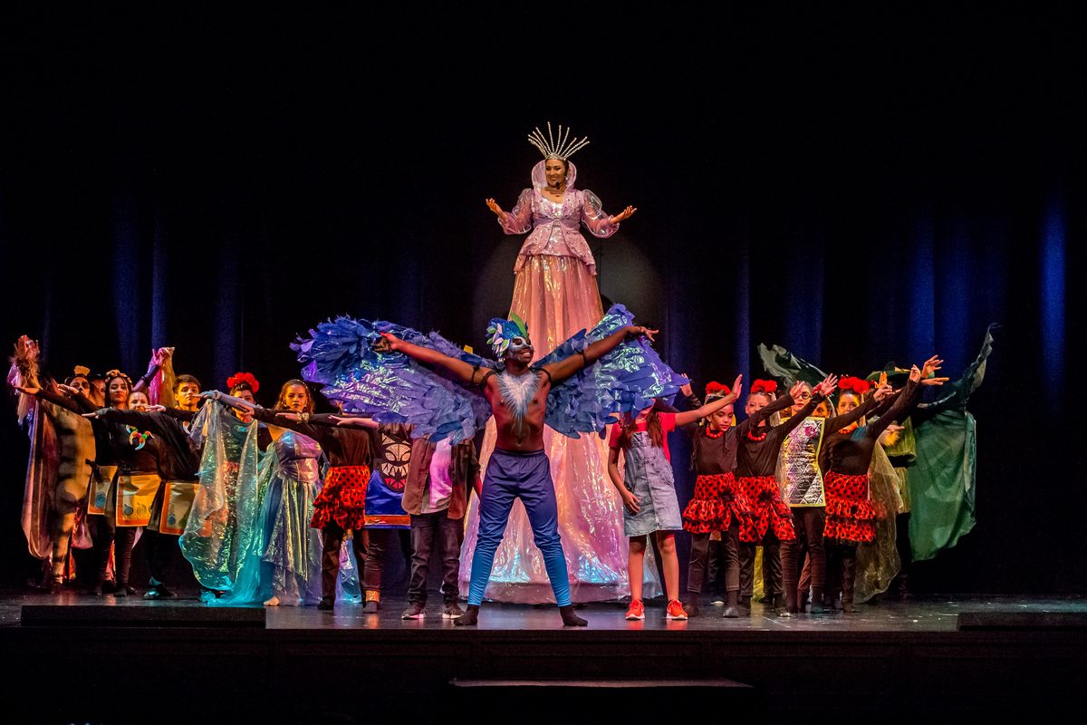 A winged character in blue at the centre of the cast