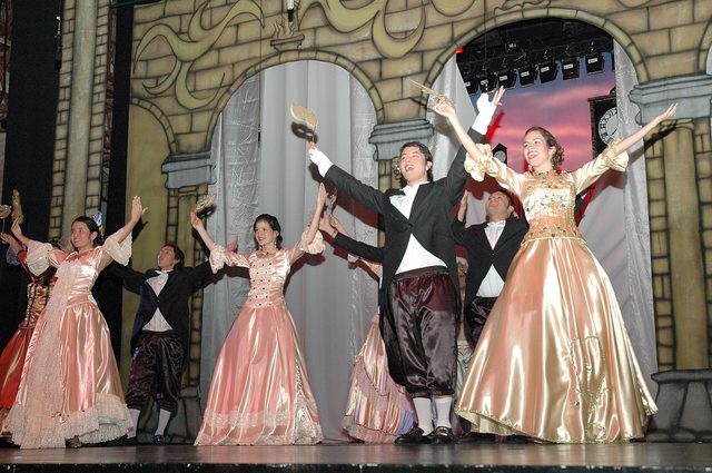 Escena de baile de salón con vestidos de época