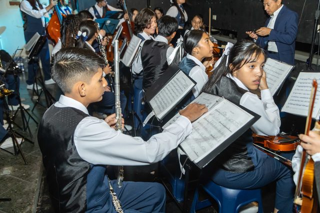 Jóvenes músicos de la orquesta leen sus partituras