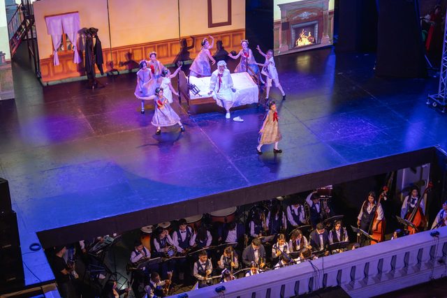 Vista desde lo alto del escenario iluminado de azul y la orquesta