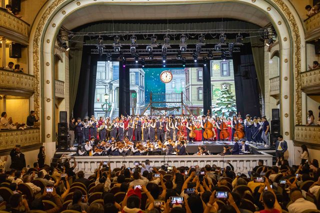 Teatro lleno, con el elenco y la orquesta en escena