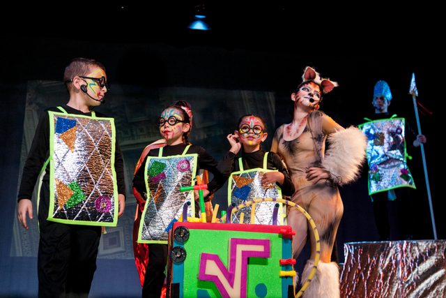 Niños con trajes plateados y personajes de animales en escena
