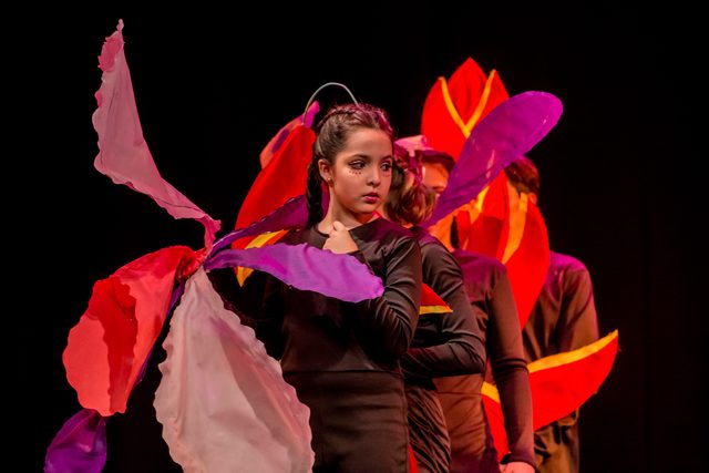 Actores con vestuario de flores rosadas y rojas