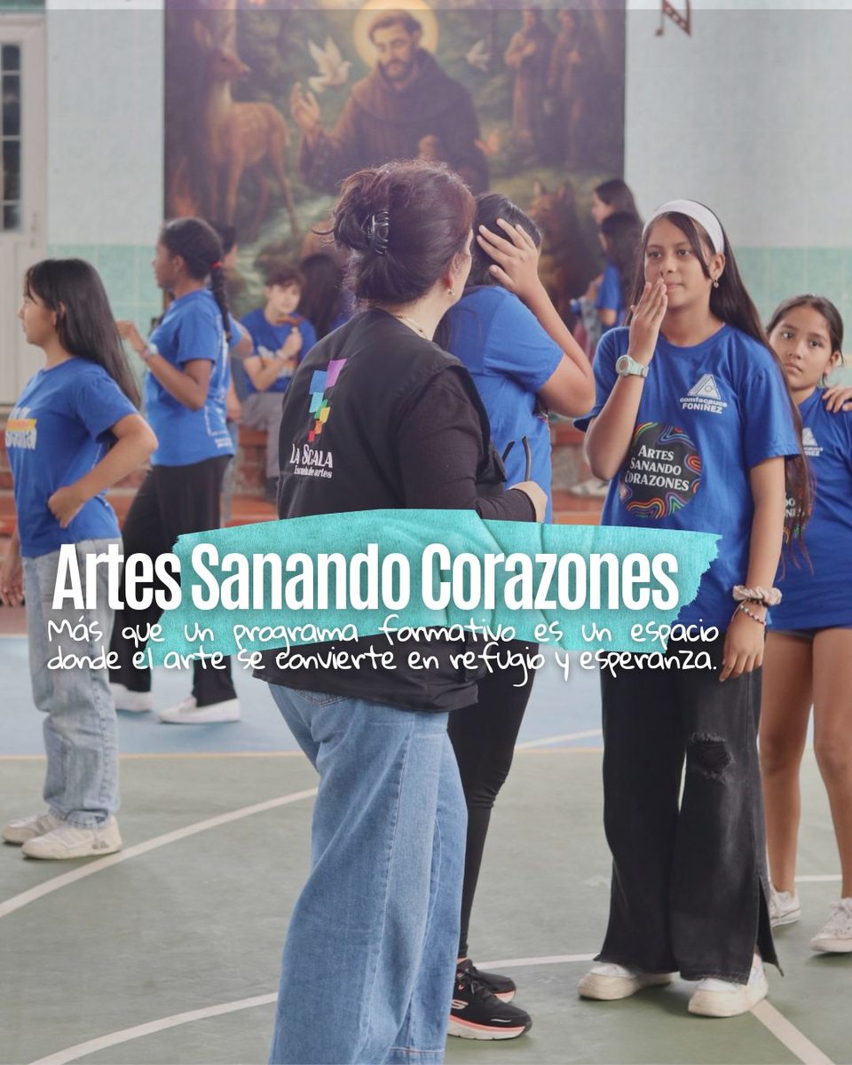 Rosana, seen from behind in a La Scala vest, talks with a young participant in a blue Artes Sanando Corazones T-shirt; the project’s motto is written over the photo