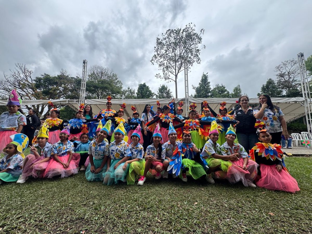 A large group of children in costume posing on the grass outdoors