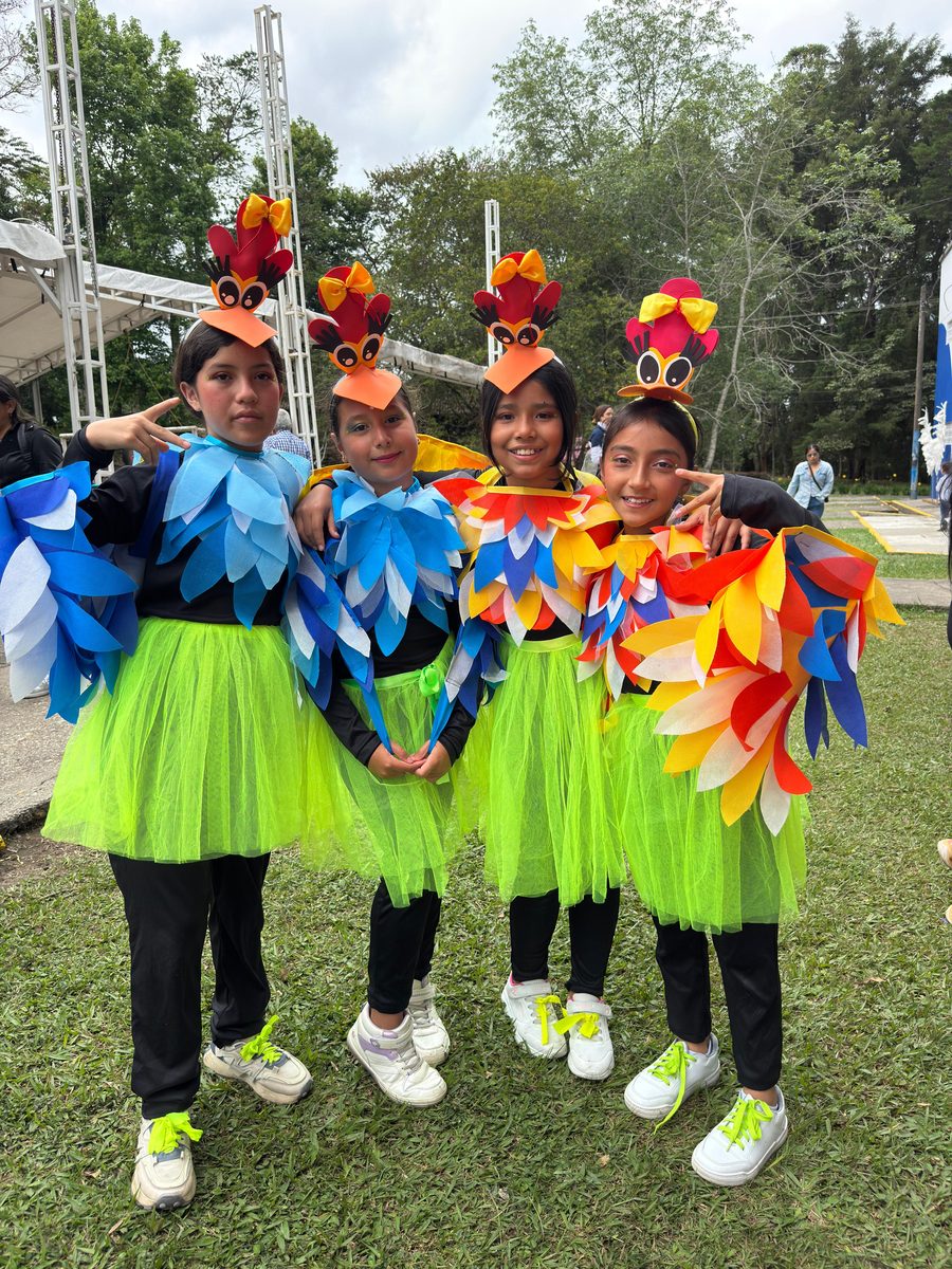 Four participants in bird costumes and green skirts posing outdoors
