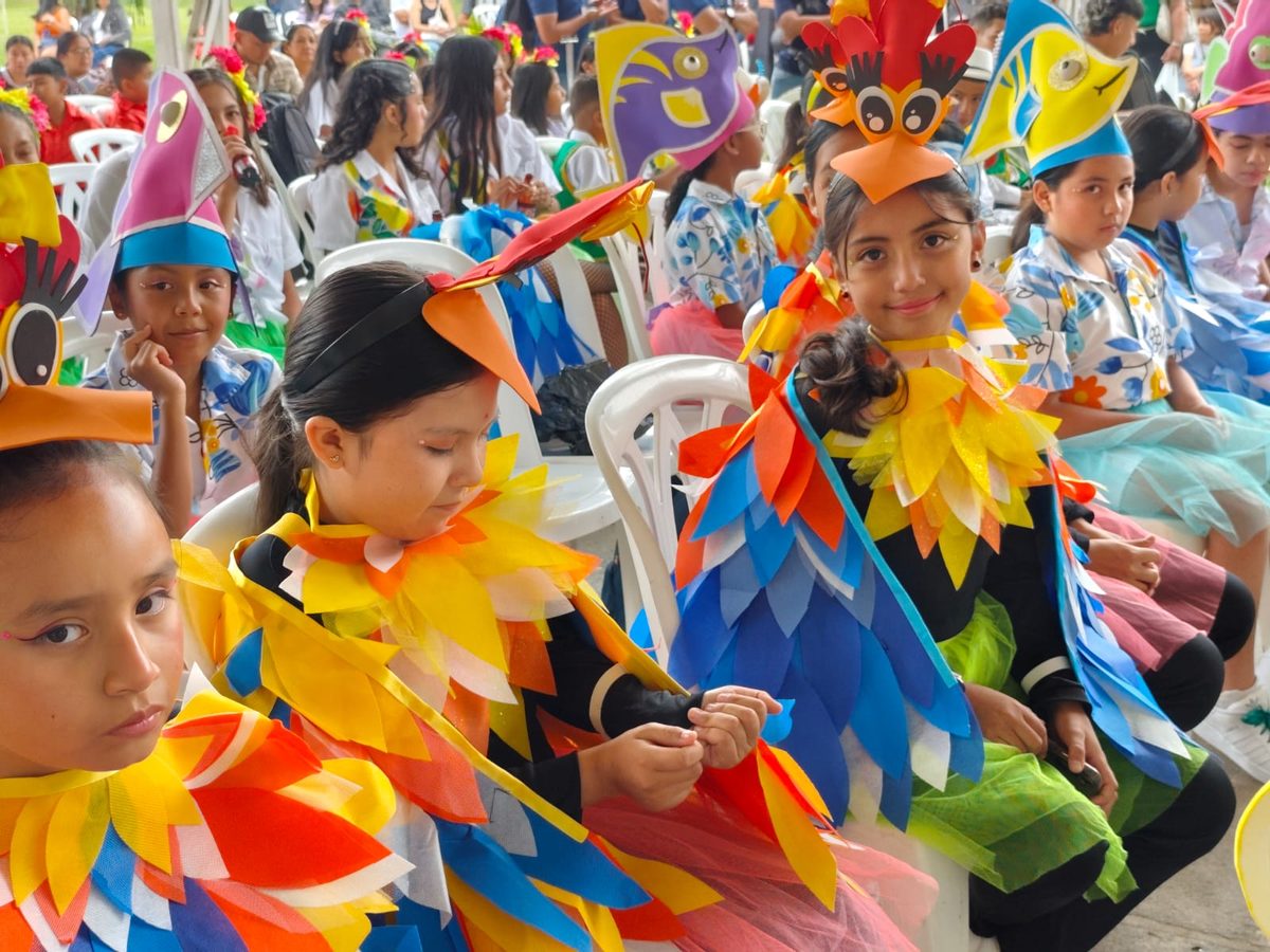 Children in colourful bird costumes waiting their turn among the audience