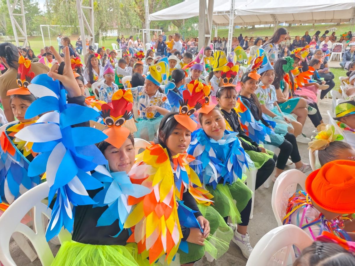 Children dressed as birds seated among the audience under a tent