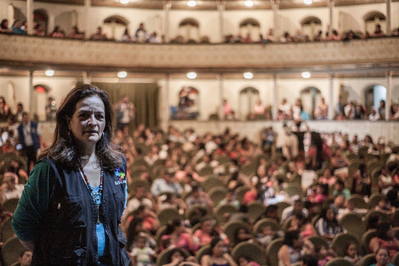Rosana standing before a full theatre