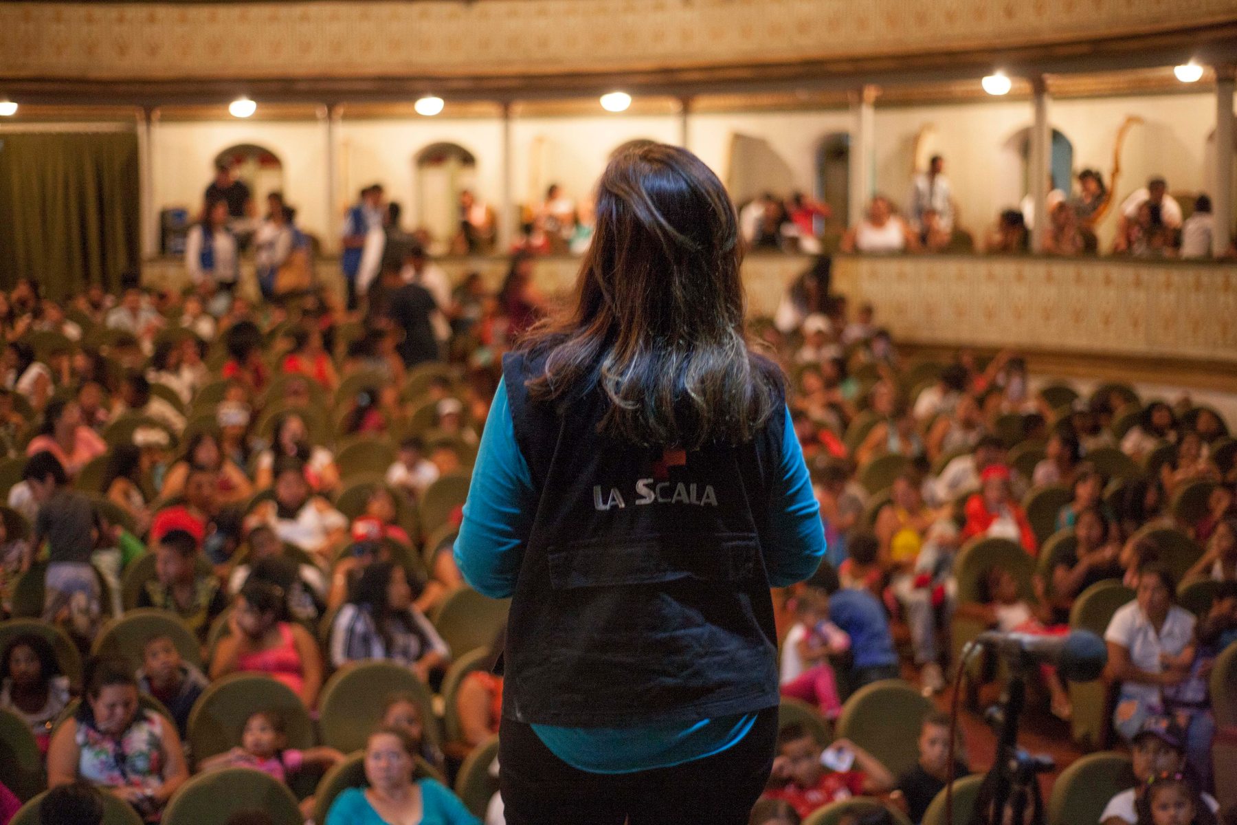 A foundation team member looks out at a theatre full of children