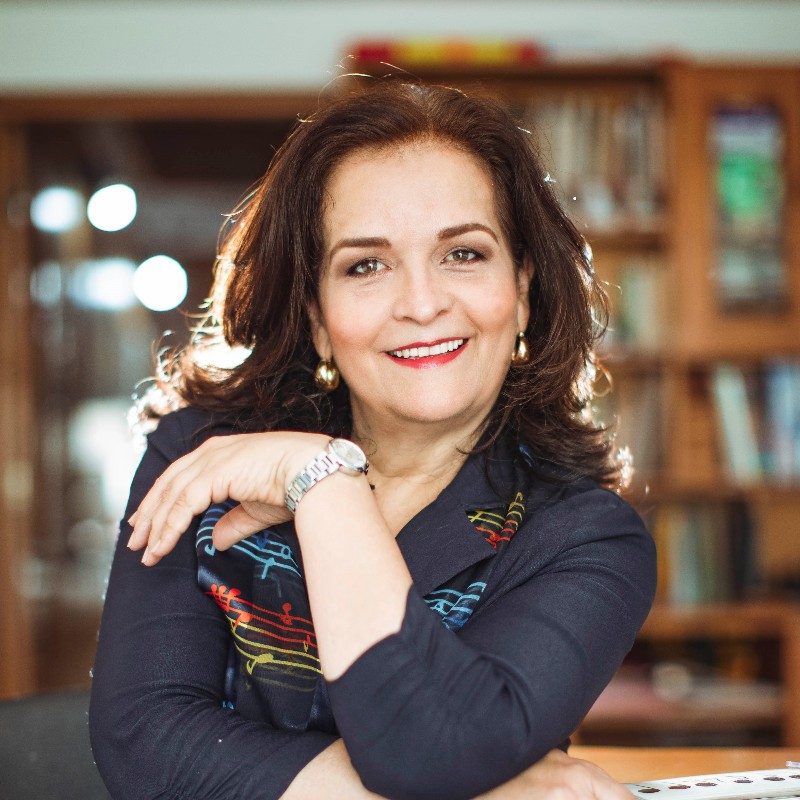 Rosana Perafán de Velasco, founder of La Scala, smiling in front of a bookcase