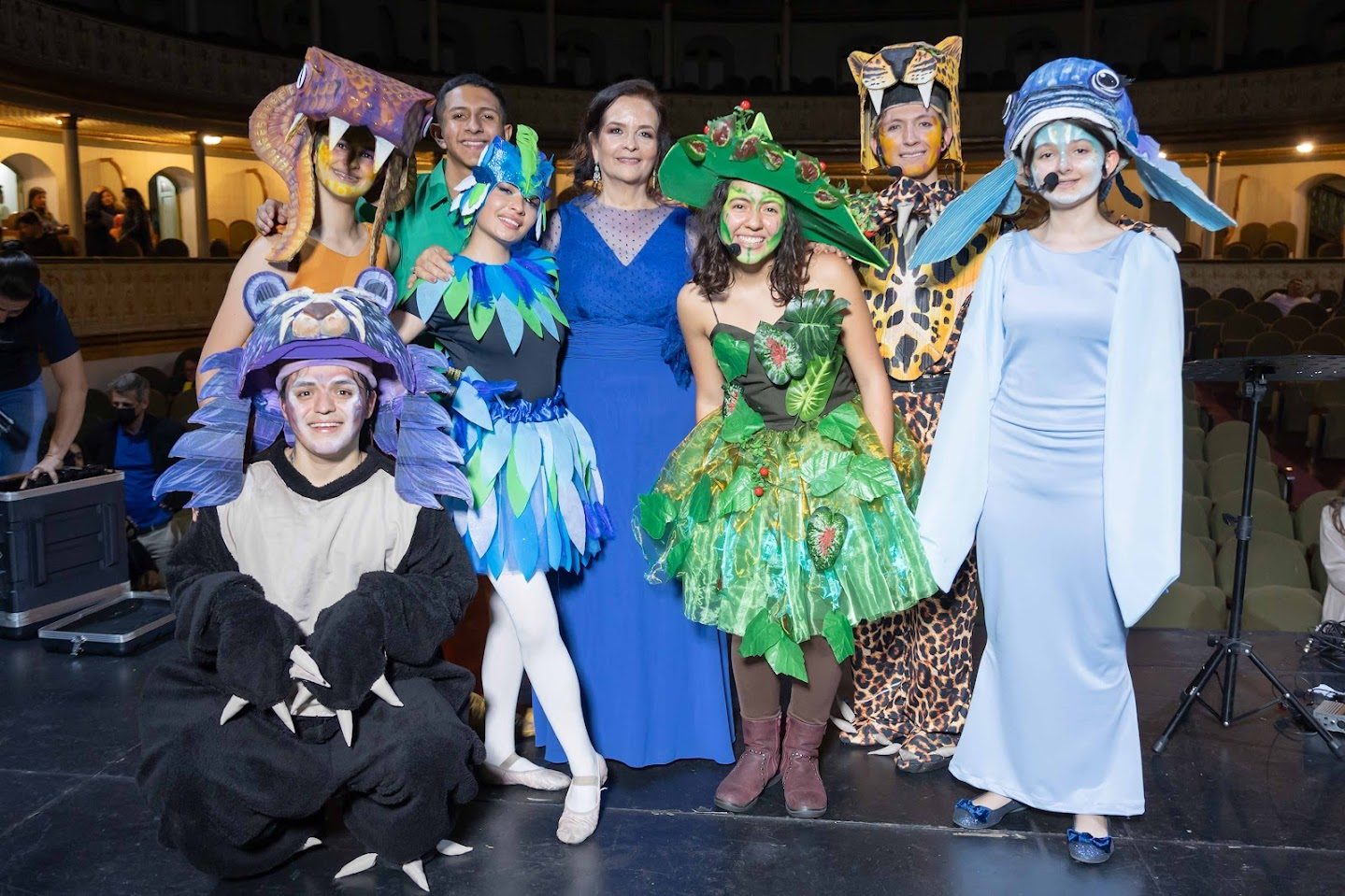 Rosana, in a blue dress, with the leads of a musical in costume